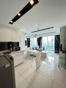 a kitchen with white cabinets and a living room at City Center Residence - Pool view in Pattaya Central