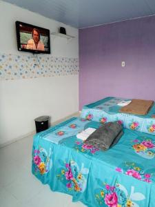 um quarto com uma cama e uma televisão na parede em Hostel das Flores em Belém