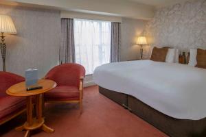 a hotel room with a large bed and a table and chairs at Old Hunstanton Le Strange Arms Hotel in Hunstanton