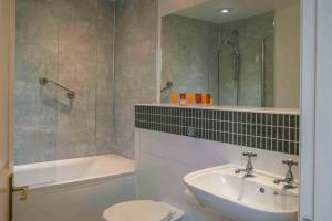 a bathroom with a sink and a toilet and a tub at Old Hunstanton Le Strange Arms Hotel in Hunstanton