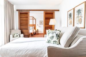 - une chambre avec un grand lit blanc et une chaise dans l'établissement Langley Resort Fort Royal, à Deshaies