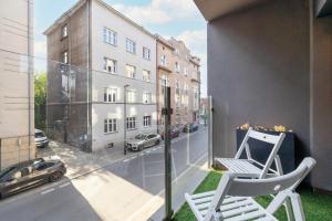 een balkon met 2 stoelen en uitzicht op een straat bij Solna Cracow Air-conditioned Apartment with Balcony by Renters in Krakau