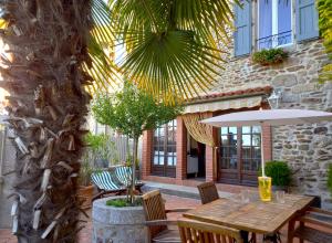 eine Terrasse mit einem Holztisch und 2 Sonnenschirmen in der Unterkunft la Maison d'Odette et Daniel in Vitrac
