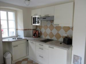 a small kitchen with white cabinets and a sink at Historisches Ferienhaus Abteistraße in Mesenich +16 photos