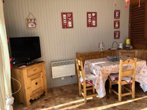 una stanza con tavolo, televisore, tavolo e sedie di L'écrin de Merlette a Orcières