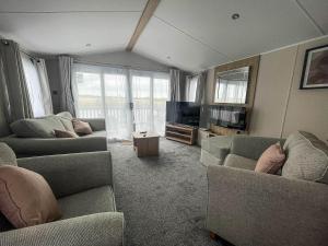 sala de estar con 2 sofás y TV en Beautiful 6 Berth Caravan With Decking, Wifi And Field Views Ref 29029sv en Clacton-on-Sea