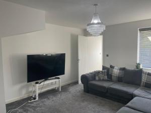 a living room with a couch and a flat screen tv at Luxury Rooms in a 3-Bedroom House, Living Room, Kitchen, Big garden only 8mins away from Coventry City Centre in Coventry