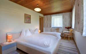 1 dormitorio con cama blanca y techo de madera en Obereinschneithof, en Schwendt