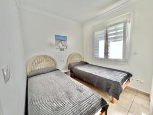 twee bedden in een kamer met een raam bij Apartamento Teresa in Oliva