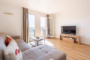 a living room with a couch and a flat screen tv at Paris la Défense, lumineux et cosy in Courbevoie