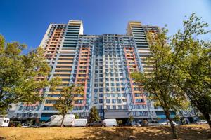 ein hohes Gebäude mit davor geparkt in der Unterkunft Kvartirkoff na Bogatyrskaya 6a, 15th floor in Kiew