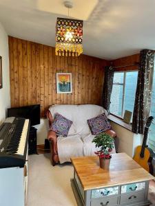 a living room with a couch and a piano at Pilgrims Rest with Annexe in Cheddar