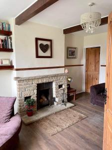 a living room with a stone fireplace and a couch at Pilgrims Rest with Annexe in Cheddar