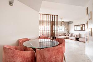 uma sala de estar com cadeiras vermelhas e uma mesa de vidro em Charmant & Spacieux 2Chambres-5 min Gare Agdal em Rabat