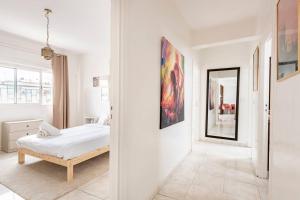 een witte slaapkamer met een bed en een spiegel bij Charmant & Spacieux 2Chambres-5 min Gare Agdal in Rabat