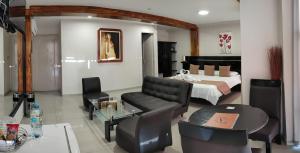 Aura Hotel في تشيكلايو: غرفة معيشة مع سرير وطاولة وكراسي