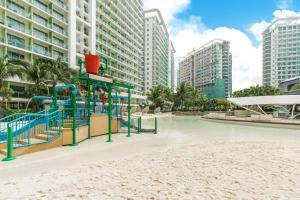 un parque infantil en medio de una playa con edificios en Resort Living 2BR Azure Urban Residences w/ Wi-Fi en Parañaque