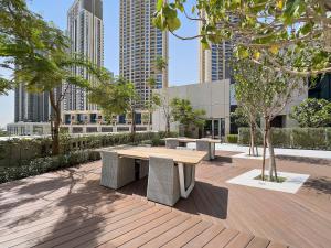 einen Holztisch und Bänke in einer Stadt mit hohen Gebäuden in der Unterkunft WelHome - Stunning Apartment With Sea Views in Creek Harbour in Dubai