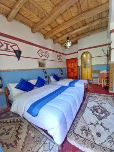 Una cama grande con sábanas azules y blancas en un dormitorio en Maison d'Hôte Argana, en Aït Idaïr