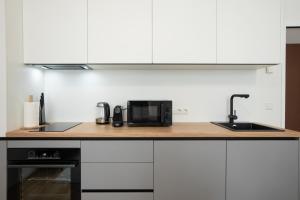 a kitchen with white cabinets and a black microwave at Modern apartment in a top location of Vienna in Vienna