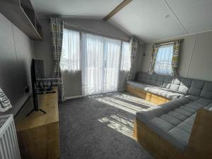 sala de estar con sofá y TV en Modern 8 Berth Caravan With Decking At Valley Farm, Essex Ref 46575v en Great Clacton