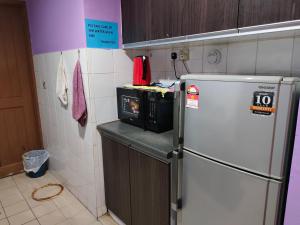 La cuisine est équipée d'un réfrigérateur blanc et d'un four micro-ondes. dans l'établissement Home Sweet Home, à Kuching