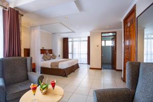 um quarto de hotel com uma cama, uma mesa e cadeiras em VICTORIA COMFORT INN em Kisumu