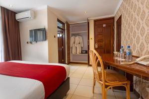 a hotel room with a bed and a desk with a desk at VICTORIA COMFORT INN in Kisumu