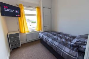 a bedroom with a bed and a window with yellow curtains at Station 14 - Vacation Home in Gelligaer