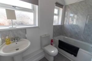 a bathroom with a sink and a toilet and a window at Station 14 - Vacation Home in Gelligaer