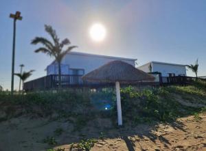 einen Strohschirm am Strand in der Nähe eines Gebäudes in der Unterkunft Casa da Praia Catembe in Maputo