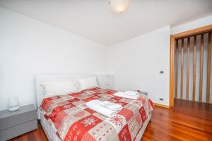 Schlafzimmer mit einem Bett mit einer roten und weißen Decke in der Unterkunft Le Coccinelle in Tarvis