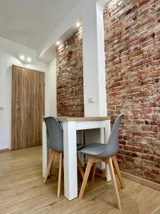 a room with a table and two chairs and a brick wall at F&F Appartments in Iglesias