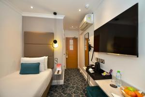 um quarto de hotel com uma cama e uma televisão de ecrã plano em Queens Park Premier London Hyde Park em Londres