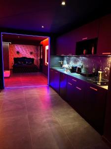 une cuisine sombre avec des placards violets et un canapé dans l'établissement LES SECRETS ROOMS - BONNEVILLE - LOVE ROOM 130m2 - SPA PRIVATIF, à Bonneville