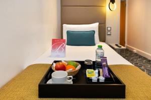 ein Tablett mit Essen auf einem Bett in einem Hotelzimmer in der Unterkunft Queens Park Premier London Hyde Park in London