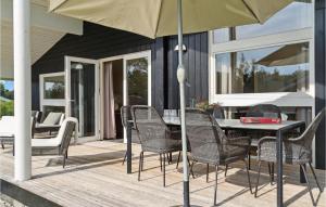 um pátio com uma mesa, cadeiras e um guarda-sol em Amazing Home In Askeby With Sauna em Askeby