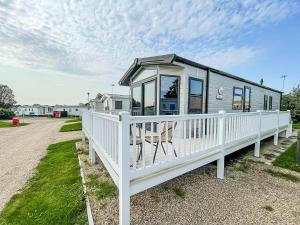 a mobile home with a porch and a white fence at Wonderful 6 Berth Caravan For Hire By A Stunning Norfolk Beach Ref 19006sd in Scratby