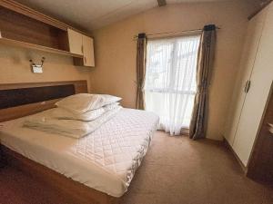 Habitación pequeña con cama y ventana en Lovely Caravan With Decking At Heacham Beach In Norfolk Ref 21028t, en Heacham