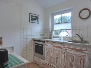 een keuken met een wastafel en een klok aan de muur bij Ferienwohnung F6 in Graal-Müritz