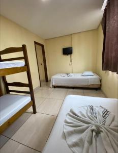 a room with two beds and a bunk bed at Pousada Elita in Divinópolis