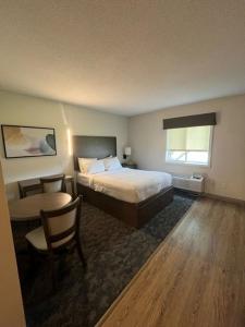 a hotel room with a bed and a table and chair at Residences at Solomon Pond in Marlborough