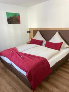 a bedroom with a large bed with red pillows at Landgasthaus zur Linde in Pleiskirchen