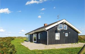 una casa negra en la playa con un patio en Awesome Home In Lkken With 4 Bedrooms, Sauna And Wifi, en Lønstrup