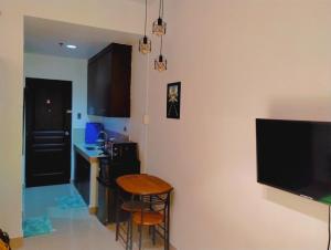 a kitchen with a table and a television on a wall at Jenny N Rose Travellers Inn in Manila
