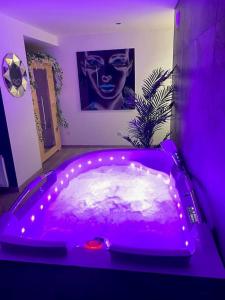 eine lila Badewanne in einem Zimmer mit einem Bild einer Frau in der Unterkunft La Suite Saphir – spa privatif in Nancy