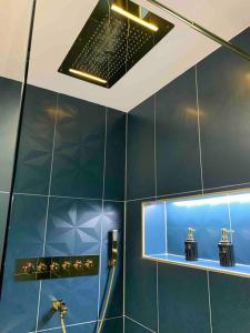 ein Bad mit blau gefliesten Wänden und einer Dusche in der Unterkunft La Suite Saphir – spa privatif in Nancy