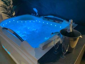 a bath tub with a bottle of wine and wine glasses at La Suite Saphir – spa privatif in Nancy