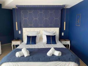 ein blaues Schlafzimmer mit einem großen Bett mit weißen Kissen in der Unterkunft La Suite Saphir – spa privatif in Nancy
