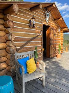 Cabaña de madera con una silla en la cubierta en Cabana do lenhador, en Espírito Santo do Pinhal